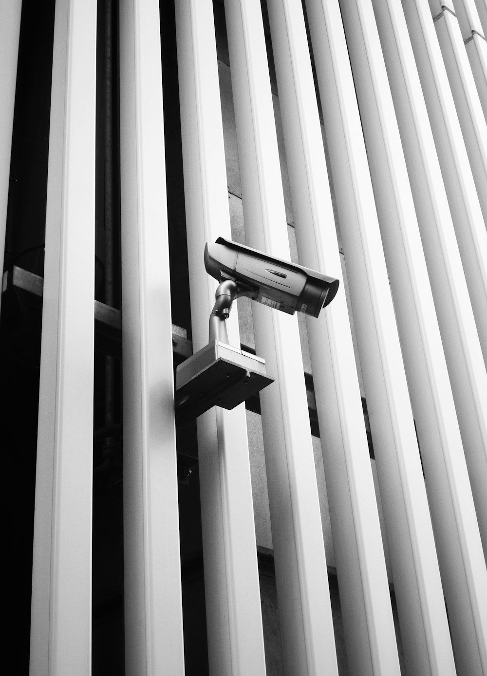 A security camera mounted on the vertical fins of a modern building