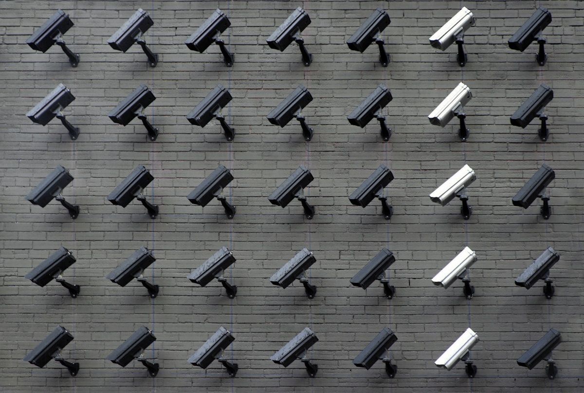 A grid of security cameras mounted across a brick wall
